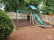 A wooden playset with swings, a slide, and a climbing area in the backyard at 2620 Merion Hills Ct, Charlotte, NC 28269