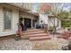 Charming home exterior features a wooden porch, double front doors, and a stone walkway, framed by flowering trees at 27 Heritage Ct, Lake Wylie, SC 29710
