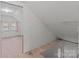 The attic has an unfinished floor, and white walls and ceiling with a window on one end at 28120 Ryan Rd, Richfield, NC 28137