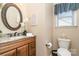 Bathroom with granite countertop vanity, oval mirror, wood cabinets, and toilet at 5115 Sand Trap Ct, Monroe, NC 28112