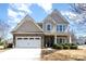 Charming two-story home featuring stone accents, attached garage and a beautifully landscaped front yard on a sunny day at 5115 Sand Trap Ct, Monroe, NC 28112