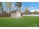 Backyard shed with a garage door and ramp, perfect for storage or a workshop, surrounded by greenery at 5467 Whiting Ave, Kannapolis, NC 28083