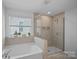 Modern bathroom featuring tiled walls, walk-in shower, garden tub and natural light at 650 Scotch Meadows Loop, Monroe, NC 28110
