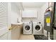 Efficient laundry room with modern washer and dryer, overhead storage, and tiled flooring at 707 Sinclair Dr, Monroe, NC 28112