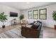 Living room featuring large windows, hardwood floors, a comfortable brown sofa, and stylish decor at 8707 Nolley Ct, Charlotte, NC 28270