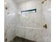 Modern shower with frameless glass, bench, black tile floor, and white marble walls at 8707 Nolley Ct, Charlotte, NC 28270