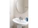 Elegant half bathroom featuring a pedestal sink, chrome faucet, round mirror, and modern wall-mounted soap dispenser at 2146 Holden Sw Ave, Concord, NC 28025