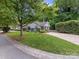 Charming home with manicured lawn, lush landscaping, and a spacious driveway, surrounded by mature trees at 2214 Olde Chantilly Ct, Charlotte, NC 28205