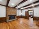 Charming living room featuring a brick fireplace, wooden beams, hardwood floors, and an entrance to a bedroom at 300 Boyd Rd, Clover, SC 29710