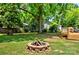 Large backyard with a fire pit, mature trees, and a wooden deck, perfect for outdoor gatherings and relaxation at 302 Griffith Rd, Monroe, NC 28112