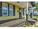 Cozy front porch, yellow siding, black shutters, and stone columns offer charming curb appeal at 302 Griffith Rd, Monroe, NC 28112