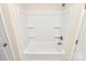 Clean white bathtub and shower combination with built-in shelving and a neutral color scheme at 3204 Leah Elizabeth Ln, Monroe, NC 28110