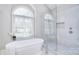Bright bathroom featuring a modern tub under an arch window and a glass shower with white tiles at 5419 Sunningdale Dr, Charlotte, NC 28277
