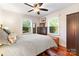 Bright bedroom with hardwood floors, a ceiling fan, two windows, and a dresser beneath a flatscreen tv at 552 Odell School Rd, Concord, NC 28027