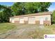 A spacious detached garage with tan siding, brick accents, and three bays sits on a green lawn surrounded by trees at 552 Odell School Rd, Concord, NC 28027