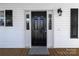 Close-up of the elegant black front door flanked by windows and black shutters, set against white siding at 6308 Brumit Ln, Charlotte, NC 28269