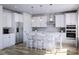 Modern white kitchen with stainless steel appliances, island seating, and pendant lighting at 7027 Short Stirrup Ln, Mint Hill, NC 28227