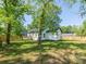 This spacious backyard includes a well-maintained lawn, mature trees, and a charming white house at 108 Graham St, Chester, SC 29706