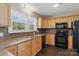 Bright kitchen with wood cabinets, stainless steel sink, black appliances, and natural light from window at 130 Atwell Rd, Mt Ulla, NC 28125