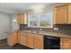 Functional kitchen with wood cabinets, double sink, black dishwasher, and a door leading to other rooms at 130 Atwell Rd, Mt Ulla, NC 28125