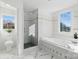 Bright bathroom featuring a glass shower, soaking tub under a window, and elegant marble floors at 13833 Jonathans Ridge Rd, Mint Hill, NC 28227