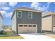 Rear view of home, featuring a large, tan garage door with windows and gray siding at 15616 Parkside Crossing Dr, Charlotte, NC 28278