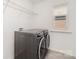 Bright laundry room boasts modern washer/dryer, storage shelves, and natural light from a window at 15616 Parkside Crossing Dr, Charlotte, NC 28278
