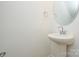 This bathroom features a pedestal sink, round mirror, and chrome fixtures at 1814 Saint Louis Nw Aly, Concord, NC 28027
