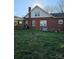 View of the backyard of a red brick home, featuring grassy area and exterior utilities at 307 Gold Hill Ave, Rockwell, NC 28138