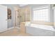 Bright bathroom featuring a glass shower and a modern soaking tub beneath a window at 3934 Blue Dory Ln, Denver, NC 28037