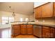 Well-lit kitchen featuring wood cabinetry, stainless steel dishwasher, and a sink with a granite countertop at 7283 Bradberry Ln, Denver, NC 28037