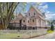 Charming two-story pink home with a white picket fence, a welcoming front porch, and mature trees at 820 N Main St, Salisbury, NC 28144