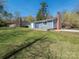 Spacious backyard with lush lawn, mature trees, and a blue home in the distance at 8432 Strider Dr, Charlotte, NC 28212