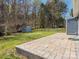 Landscaped backyard featuring a stone patio and a storage shed with mature trees, perfect for relaxation and outdoor activities at 8432 Strider Dr, Charlotte, NC 28212