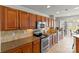Bright kitchen showcasing stainless steel appliances, stylish backsplash, and warm wooden cabinetry with plentiful storage space at 103 Karlyn Ct, Mooresville, NC 28115