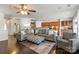 Open-concept living room with a stylish gray sectional, ceiling fan, and dark hardwood floors flowing into the kitchen area at 103 Karlyn Ct, Mooresville, NC 28115
