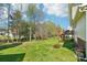 Spacious backyard featuring green grass, scattered trees, a wooden fence, and a wood deck attached to the house at 11615 Hidden Grove Trl, Charlotte, NC 28215