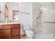 Bright bathroom with white tile shower, glass door, wood vanity, and granite countertop at 127 Castle Dr, Mooresville, NC 28117