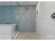 Modern bathroom features a walk-in shower with blue tile and glass enclosure, and pebble tile flooring at 127 N Tryon St # 615, Charlotte, NC 28202