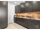 Stylish wet bar with dark cabinets, stone backsplash, and ample storage space at 127 N Tryon St # 615, Charlotte, NC 28202