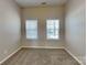 An empty bedroom with carpet, two windows, and light beige walls create a peaceful retreat at 2122 Shumard Cir, Indian Trail, NC 28079