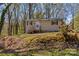 Charming tan home with black trim and front porch nestled among trees on a sunny day at 216 E Georgia Ave, Bessemer City, NC 28016
