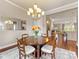 Open-concept dining room with a wood table and seating for four illuminated by a chandelier at 266 Iverson Way, Charlotte, NC 28203