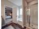 Bright bathroom showcasing a soaking tub, glass-enclosed shower, and stylish fixtures next to a view into the main bedroom at 3810 New Salem Rd, Monroe, NC 28110