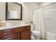 Well-lit bathroom with a wood vanity, neutral walls, and a tub with a shower behind a decorative curtain at 39617 Rosebay Ct, Fort Mill, SC 29707