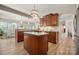 Open kitchen featuring a central island, wood cabinets, granite counters, and an elegant light fixture at 39617 Rosebay Ct, Fort Mill, SC 29707