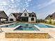 Stunning backyard featuring a large pool, spa, and covered patio with a modern white brick home in the background at 406 Sugar Maple Ln, Weddington, NC 28104