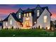 Striking exterior elevation featuring dramatic lighting, manicured lawn, and lush landscaping at 406 Sugar Maple Ln, Weddington, NC 28104