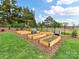 Well-maintained raised garden beds in a fenced backyard, surrounded by manicured lawn and lush trees at 406 Sugar Maple Ln, Weddington, NC 28104