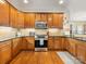Spacious kitchen boasts wooden cabinets, stone backsplash, stainless steel appliances, and hardwood floor at 4434 Patriots Hill Rd, Mint Hill, NC 28227